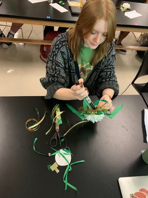 Floral Design student Savannah Okland makes a wrist mum during class. Courtesy of Sarah Kennedy. 